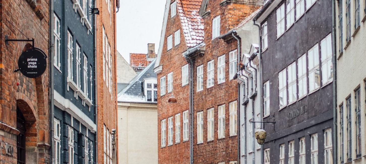 A woman cycles down snowy Magstræde in Copenhagen, Denmark