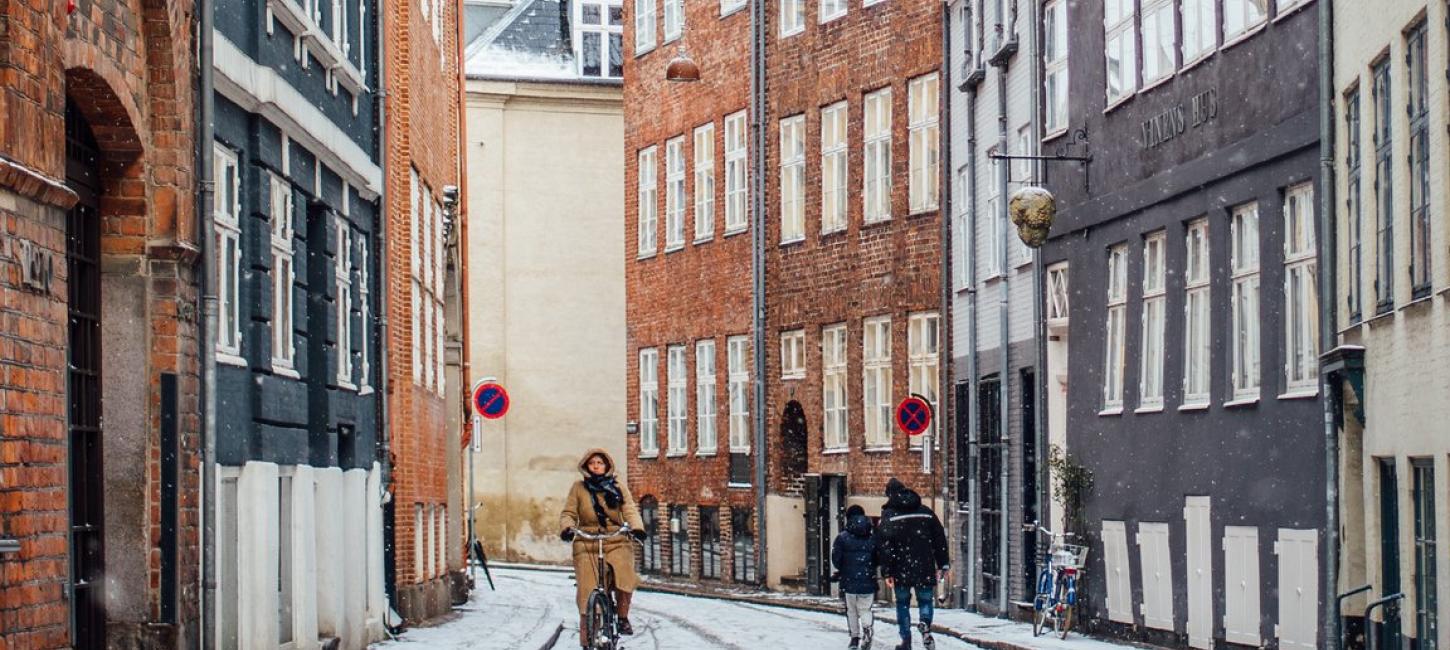 A woman cycles down snowy Magstræde in Copenhagen, Denmark