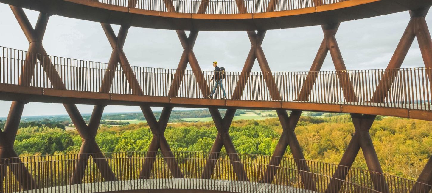 A man walks up Camp Adventure, a forest tower in Denmark.