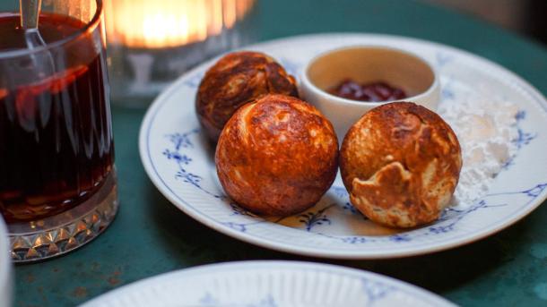 Das Bild zeigt ein traditionelles dänisches Weihnachtsdessert "Æbleskiver" und Gløgg, was dasselbe ist wie Glühwein.