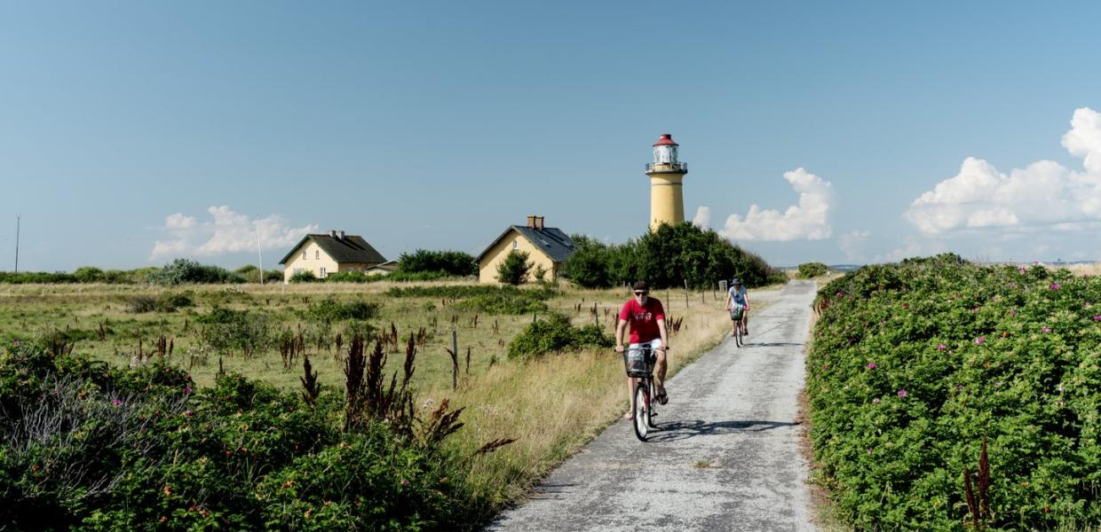 Fietsers passeren de Omø Fyr vuurtoren op het Deense eiland Omø