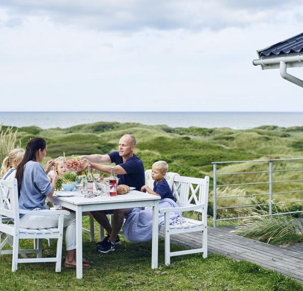 Famile ist Mittagessen auf der Terrasse eines Ferienhauses in Dänemark